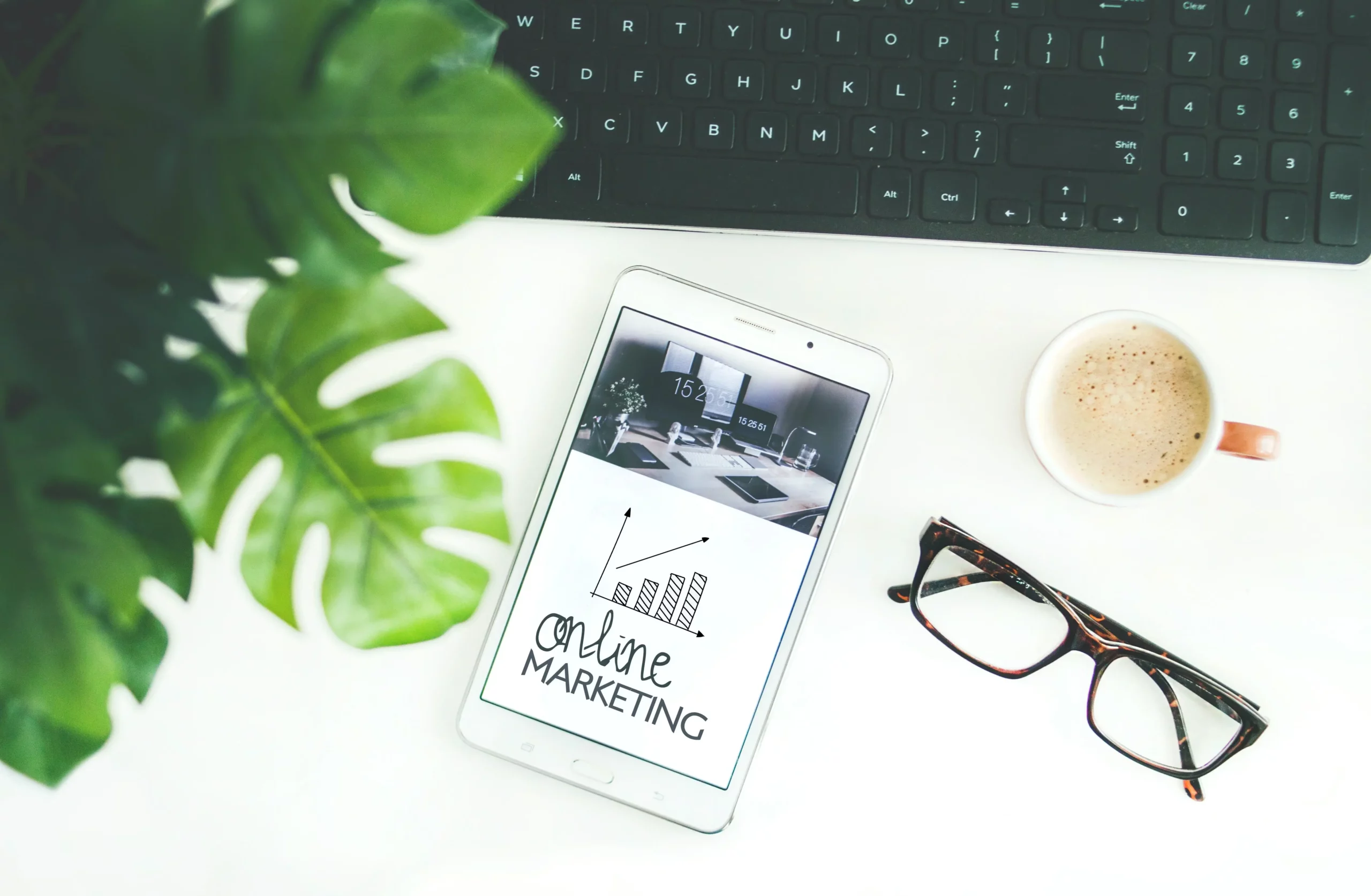 Tablet z napisem online marketing na biurku obok kawy i okularów – digital marketing w praktyce