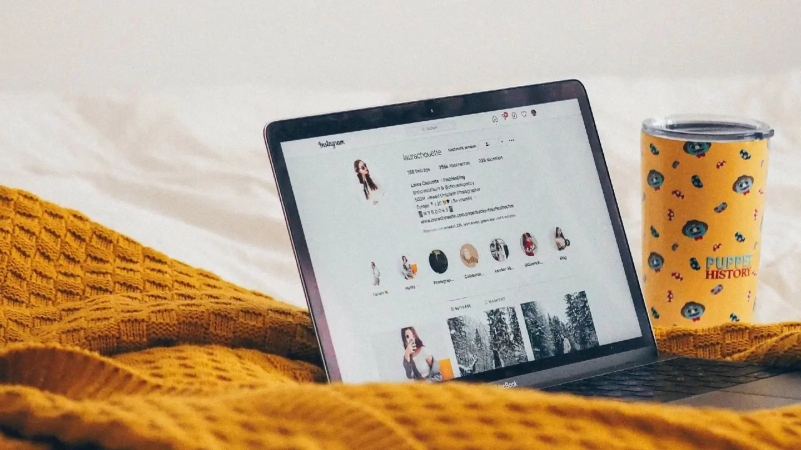 Influencer pracujący nad profilem na Instagramie – laptop, kubek i koc w domowym otoczeniu
