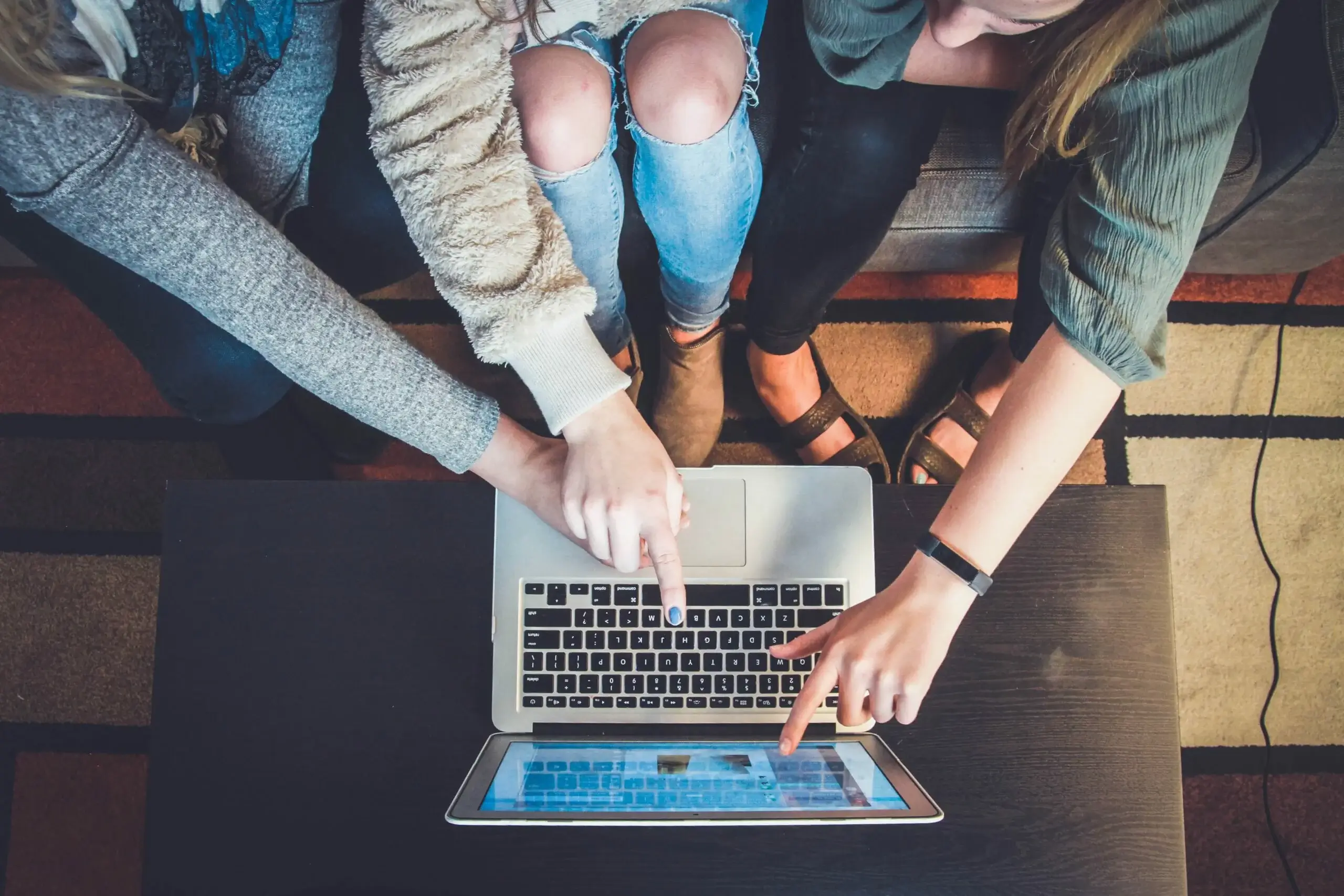 Osoby pracujące przy laptopie omawiające kampanie reklamowe i strategie marketingowe online.